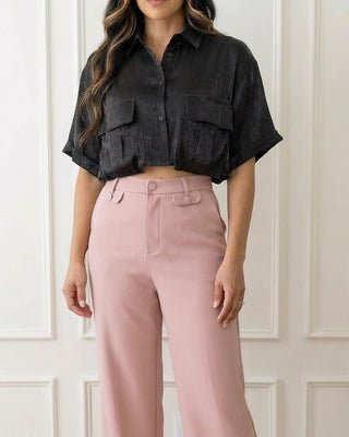 Woman wearing a black short-sleeve crop shirt and blush pants 
