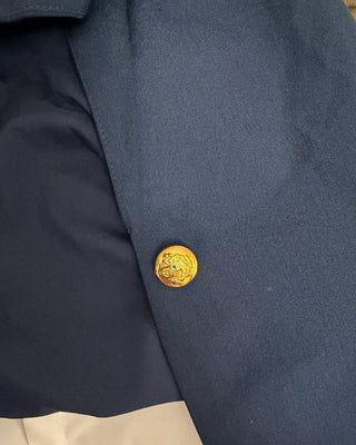 Close-up of a navy blue blazer with a gold antique style button