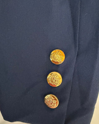 Close-up of a navy blue blazer sleeves with a gold antique style button