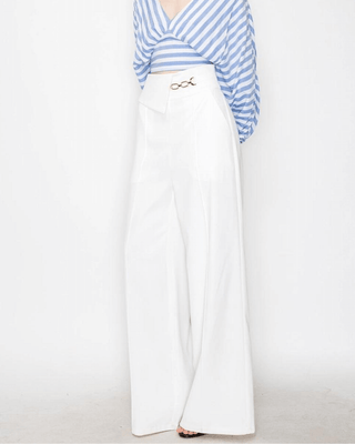 A pair of high-waisted, white wide-leg trousers with flap chain detail and pockets with zippers on the back.